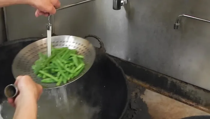 Immediately rinse the cooked green beans with cold water to stop the cooking process and prevent them from becoming too soft.