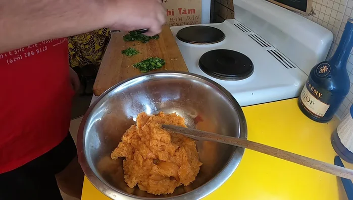 Transfer the mixture to a bowl. Add chopped green chili, kaffir lime leaves, and basil. Mix well.