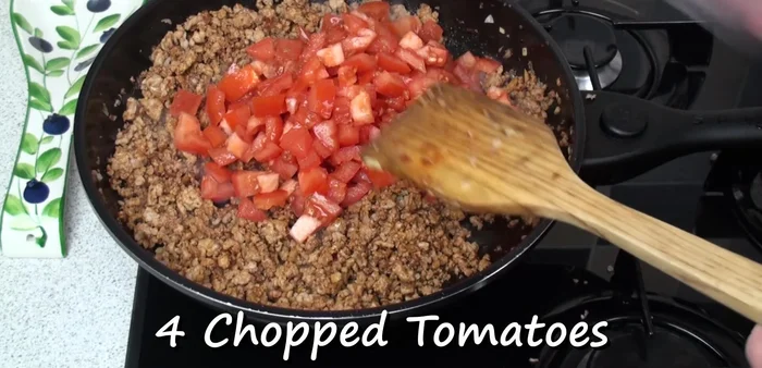 Add four chopped plum tomatoes. Mix well, season with pepper, and continue cooking for about 5 or 6 minutes.