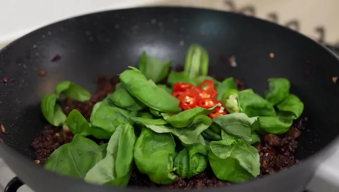 Turn off the heat. Add fresh basil leaves, mild chilies, and black pepper. Mix well.