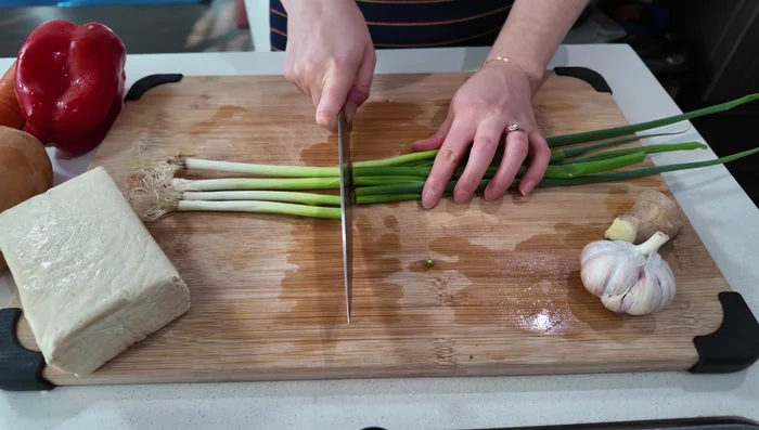 Prep vegetables: Mince green onions (separate white and green parts), chop broccoli into florets (separate stems and florets), chop bell pepper, carrot, and sweet potato. Mince garlic and ginger finely.