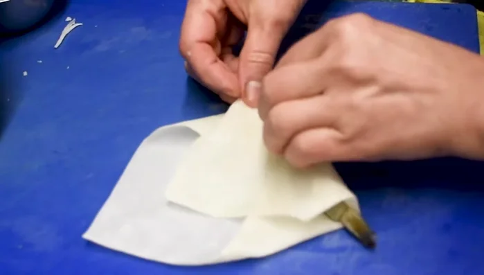 Roll the spring roll tightly and seal completely using water as glue. (314.08)
