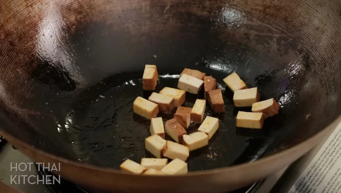 Combine the ingredients: In a pan, gently break the crispy noodles into smaller pieces and heat them through. Add the bean sprouts, garlic chives, and a portion of the egg ribbons. Toss to combine and slightly soften the noodles.