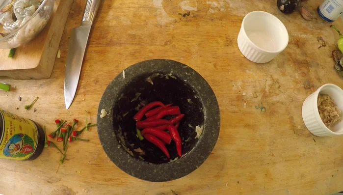 Remove stems from chilies and roughly mash them in the mortar and pestle.