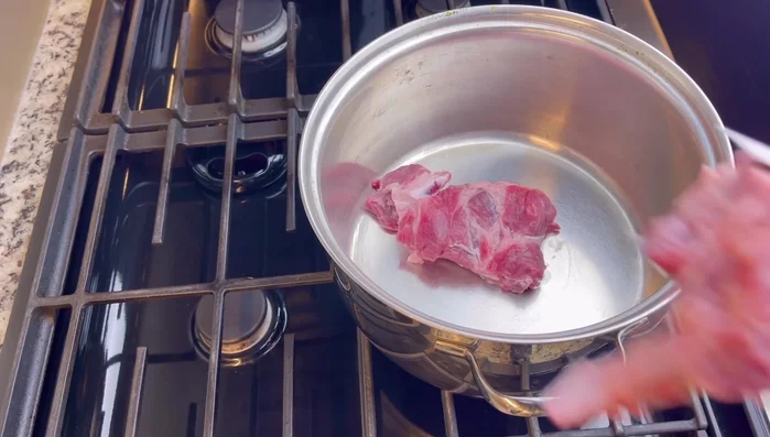 Clean pork neck bones by rinsing them under hot water.