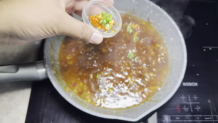 Add red and green chilies to the sauce.