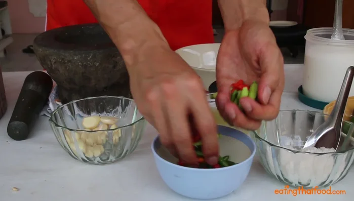 Pound garlic and chilies with a mortar and pestle until oils release (about 5 minutes).