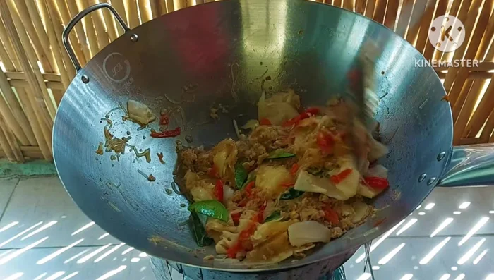 Add shredded kaffir lime leaves and sliced red chili peppers. Stir-fry again.