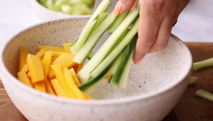 Add mango, cucumber, and shredded red cabbage to a bowl.