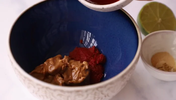 Make the dressing by whisking together Thai red curry paste, peanut butter, maple syrup, garlic and ginger powder, lime juice, and water.