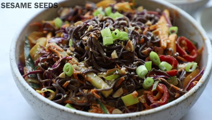 Serve in a bowl, garnished with chopped peanuts, green onions, and sesame seeds.