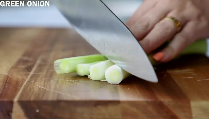 Slice green onions and place them in a bowl with the shredded carrots.