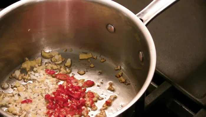 Mince serrano peppers and add them to the pan along with about half a teaspoon of red chili paste. Saute for 30 seconds to a minute.