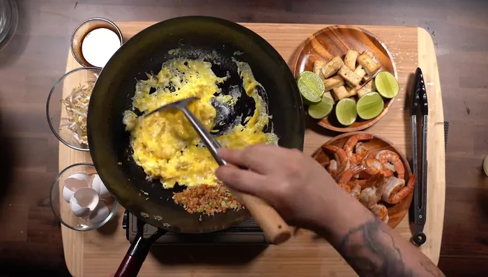 Combine noodles, aromatics, protein and sauce: Add the soaked noodles to the wok, along with the cooked eggs, tofu, shrimp, and Pad Thai sauce. Toss to combine.