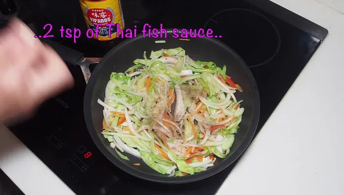 Season with black pepper, fish sauce, and oyster sauce. Add the Thai basil and stir-fry for another 2 minutes.