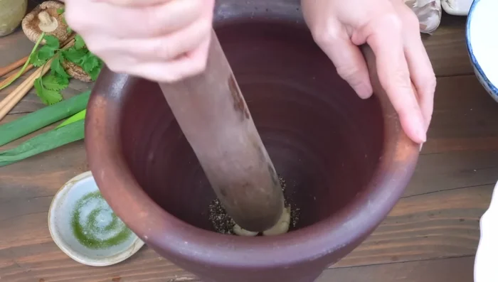 Crush pepper and garlic. Combine with coriander stalks to release flavors.