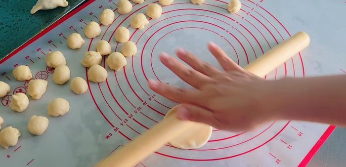 Assemble the Khanom Pang: Roll out each dough piece thinly. Place about 5-6 grams of filling in the center. Seal the edges tightly. (352.919)