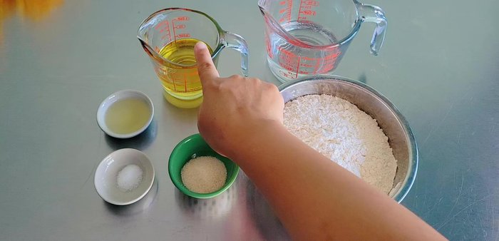 Make the dough: Combine flour, sugar, and a little salt. Make a well in the center and add vegetable oil and water gradually, mixing until a dough forms. Knead for 5 minutes, adding more water if needed. Add another tablespoon of oil and knead until smooth.