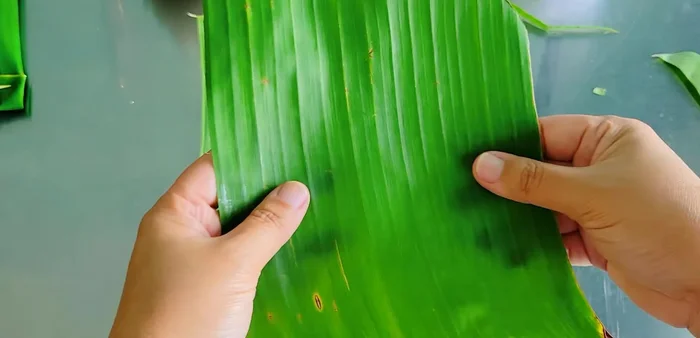 Prepare banana leaves: Lay two leaves shiny-side down, overlapping slightly. Place sticky rice and taro filling in the center. (282.68)