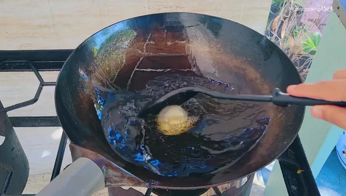 Heat enough vegetable oil in a wok or frying pan over medium-low heat. Fry the dough balls one at a time, ensuring they don't stick together.