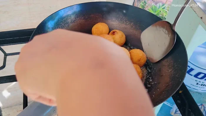 Add the fried dough balls to the sugar syrup and stir quickly until evenly coated. Turn off heat and continue stirring until the sugar crystallizes.