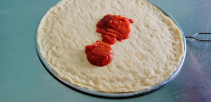 Spread pizza sauce over the dough. Add cheese, then pork larb, shallots, and another layer of mozzarella cheese.