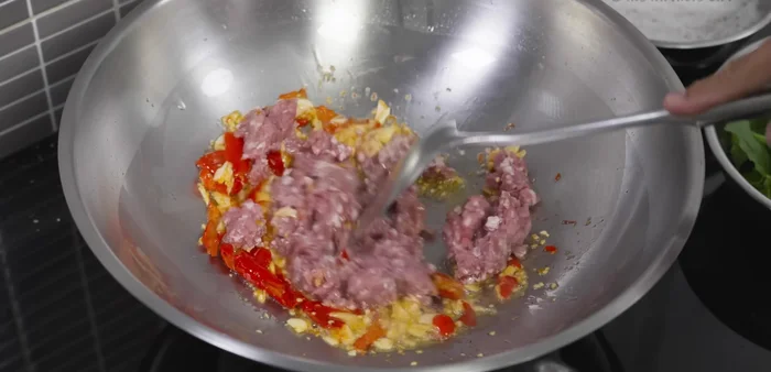 Add minced pork and stir-fry until about 60-70% cooked.