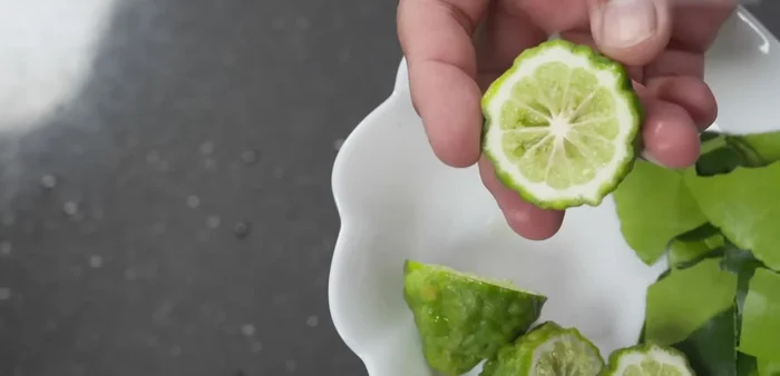 Prepare the kaffir lime by washing, cutting in half, and removing the seeds.