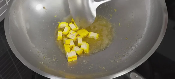 Add tofu to the pan and stir-fry until lightly browned. Add noodles and a little water, stir-fry until noodles soften. Add Pad Thai sauce, chili powder (optional), and stir well.