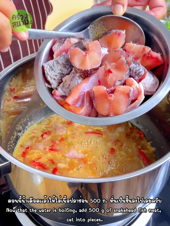 Add the cleaned and cut snakehead fish to the boiling curry mixture. Stir gently to prevent the fish skin from breaking.