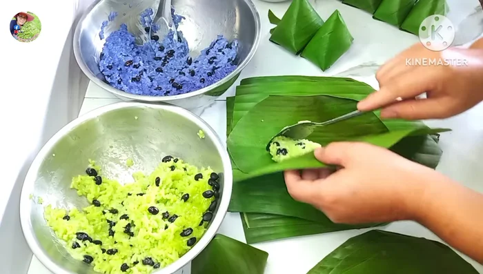Wrap the sticky rice: Use banana leaves to wrap the rice, alternating colors and adding banana slices inside. Press firmly to shape.