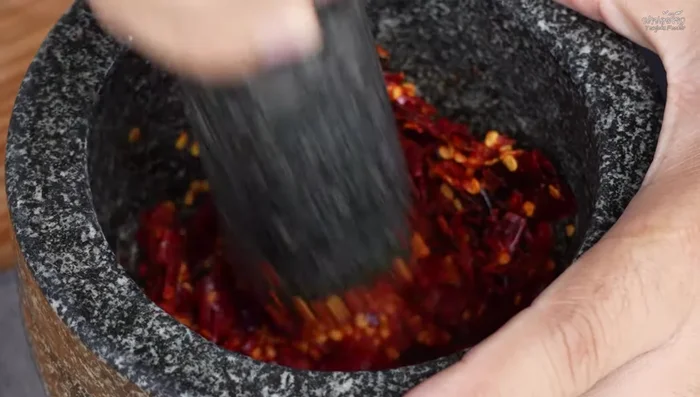 Pound the shallots, galangal, and other curry paste ingredients in a mortar and pestle. (Add ingredients gradually)