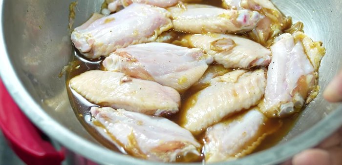 Arrange the marinated chicken wings in the air fryer, ensuring they don't overlap.