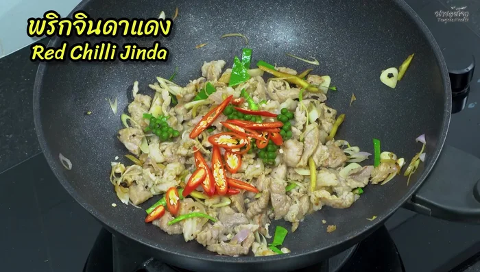 Add peppercorns and chilies: Add the young peppercorns, sliced red and green chilies. Stir-fry until cooked.
