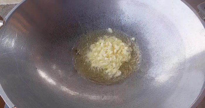 Heat vegetable oil in a wok or pan. Add chopped garlic and fry until fragrant.