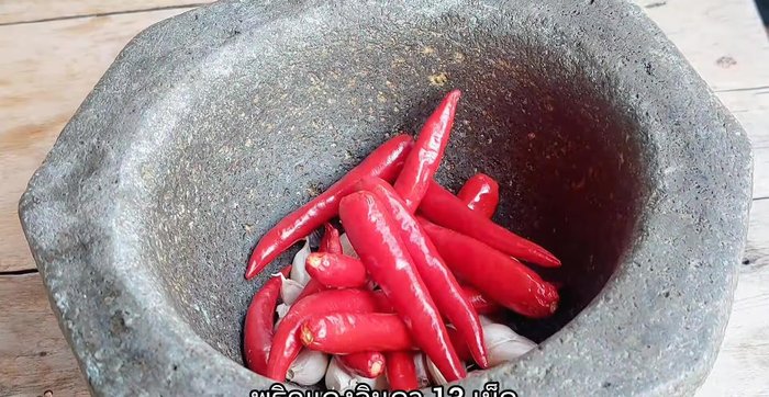 Pound garlic and chili peppers using a mortar and pestle.