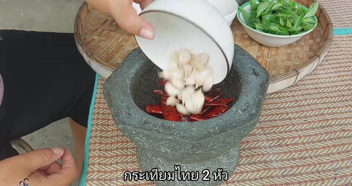 Pound garlic and dried chilies together using a mortar and pestle.