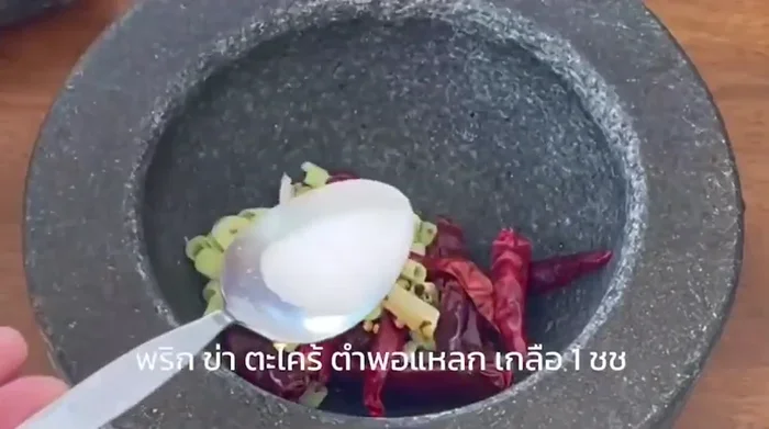 Prepare the curry paste: Combine Thai chili paste, galangal, lemongrass, garlic, and shallots. Grind to a fine paste using a mortar and pestle or food processor. [This step is inferred from the video and common Aom Kreuang Nai Moo preparation.]