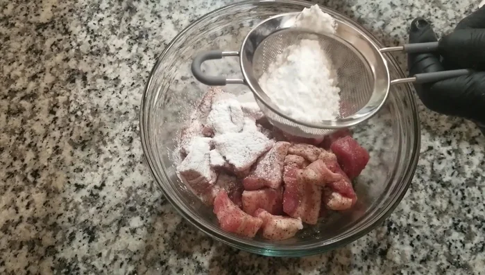 Coat the marinated pork belly in the flour mixture using a strainer.