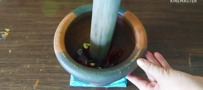 Pound the roasted chilies, shallots, and garlic into a paste.