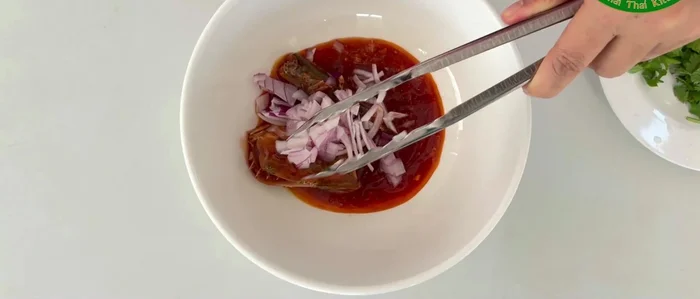 Add the sliced shallots, lemongrass, and fresh chili to the bowl.