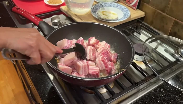 Add pork belly. Reduce heat to low, ensuring garlic and palm sugar are well combined with the pork.