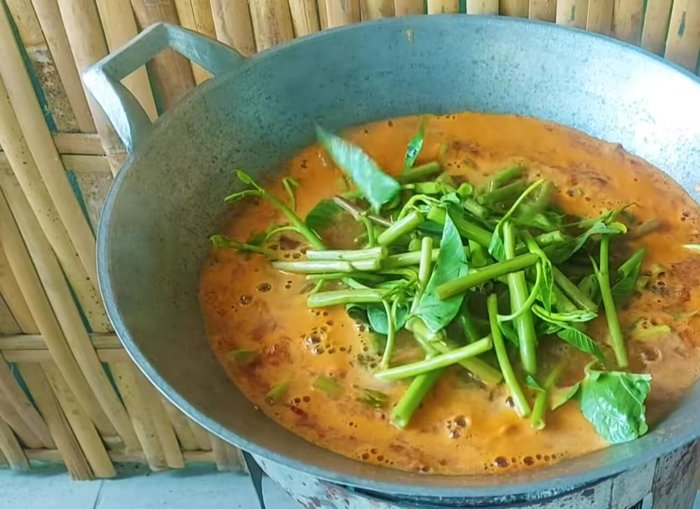 Once boiling, add the morning glory and canned fish. Do not add extra water.