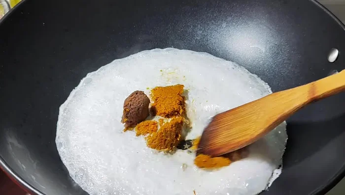 Add the curry paste and shrimp paste mixture to the simmering coconut milk and stir to dissolve.