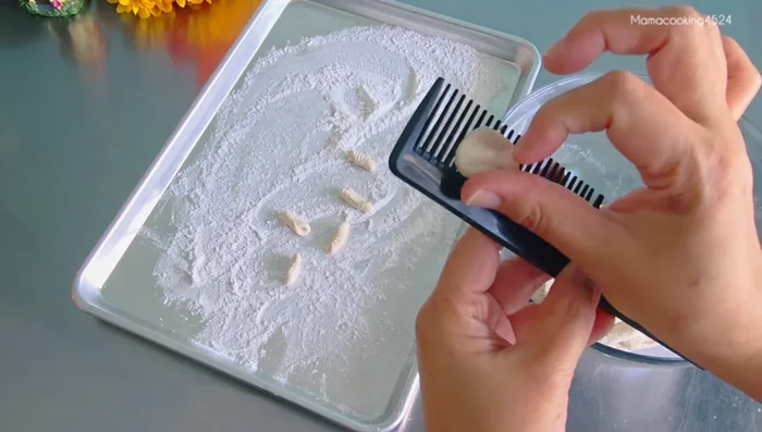 Shape the dough into small balls and roll them gently on the comb to create the canal shape. Avoid pressing too hard.