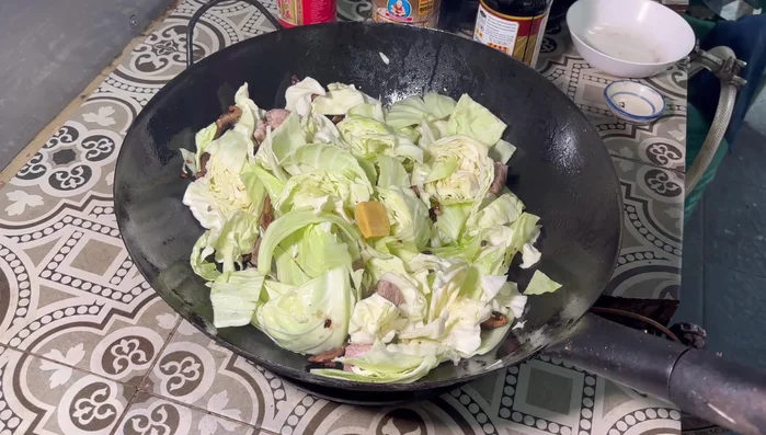 Add soup cubes, salt, pink salt, white mushrooms, oyster sauce, and dark soy sauce. Stir-fry for 4-5 minutes until well mixed.