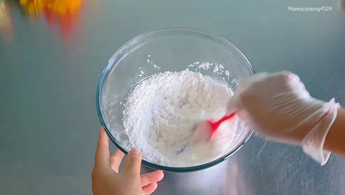 Gradually add 130ml of boiling hot water to the flour mixture, mixing continuously until a soft, less sticky dough forms.