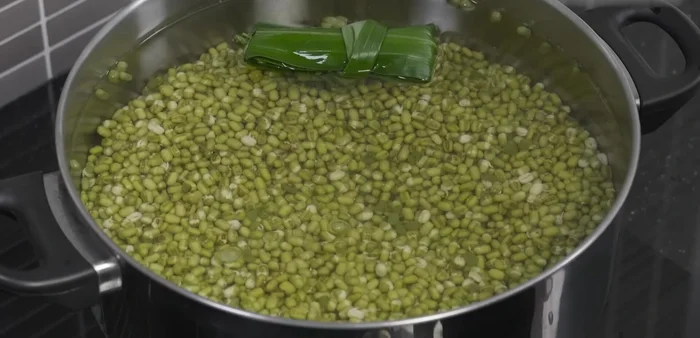 Once boiling, reduce heat to medium-low, add pandan leaves, cover, and simmer until mung beans are partially cooked but still firm.