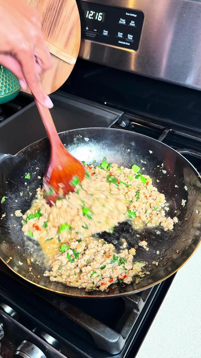 Finish and serve: Add MSG (optional). Taste and adjust seasoning if needed. Serve hot over rice, garnished with extra chilies and Thai basil.
