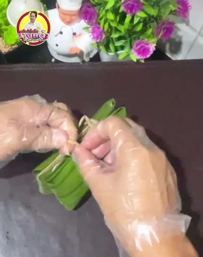 Tie the wrapped Khao Tom Mat securely with string or banana plant fiber.